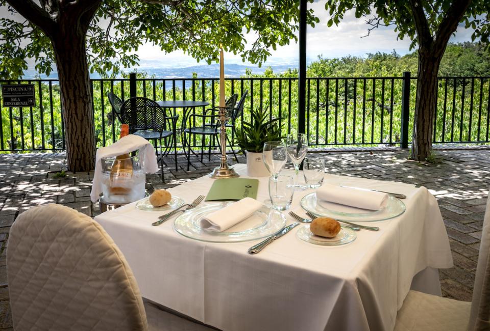 Tavolo elegante all'aperto con vista panoramica e champagne in secchiello.